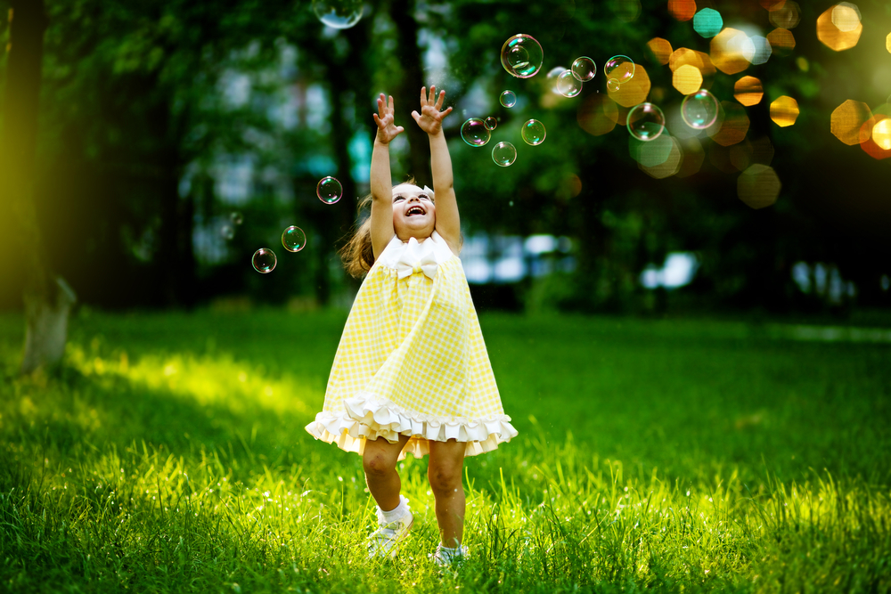 Девочка ловит мыльные пузыри на природе