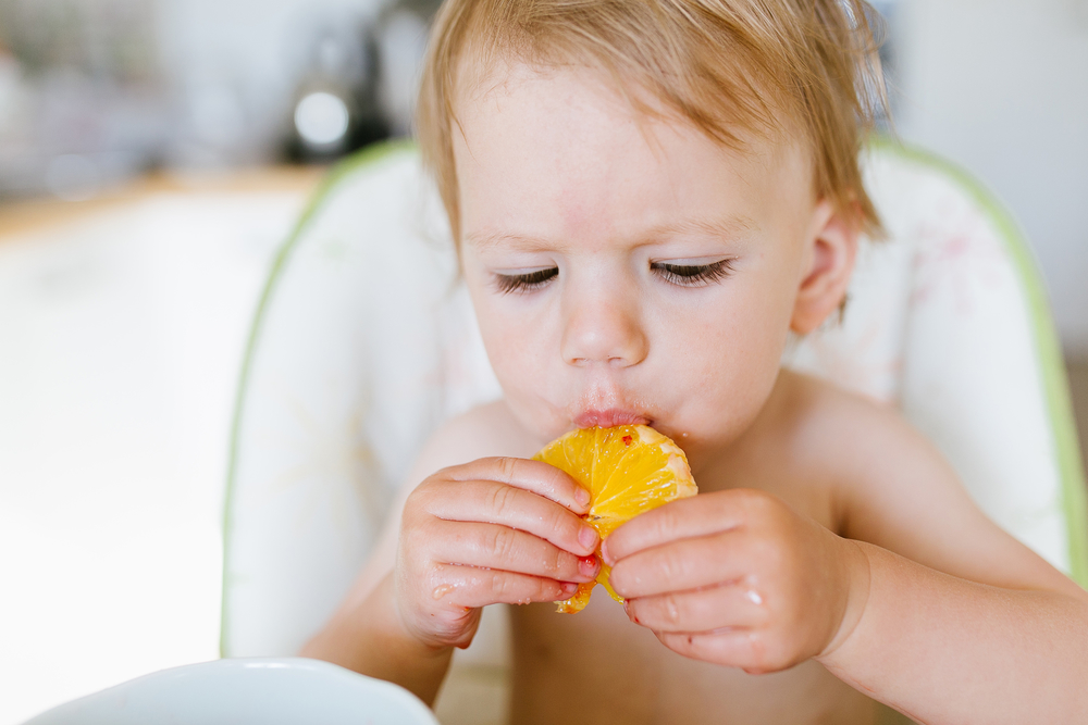 Малыш ест апельсин