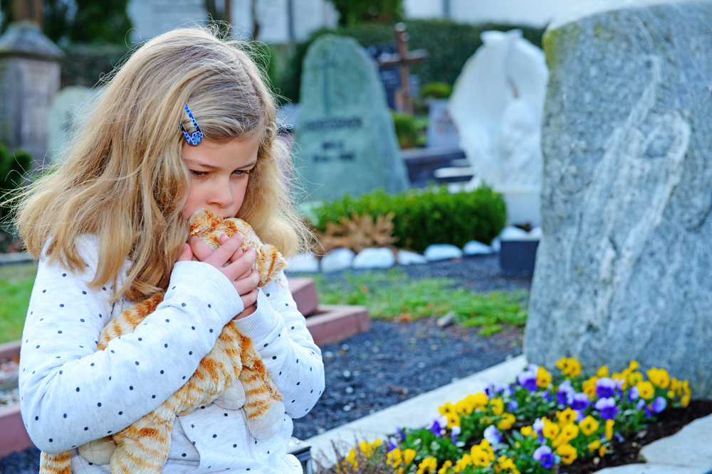 Девочка молится на кладбище