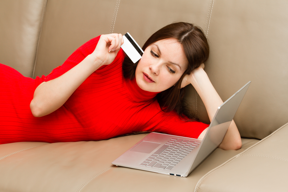 Женщина лежит на диване с картой и ноутбуком