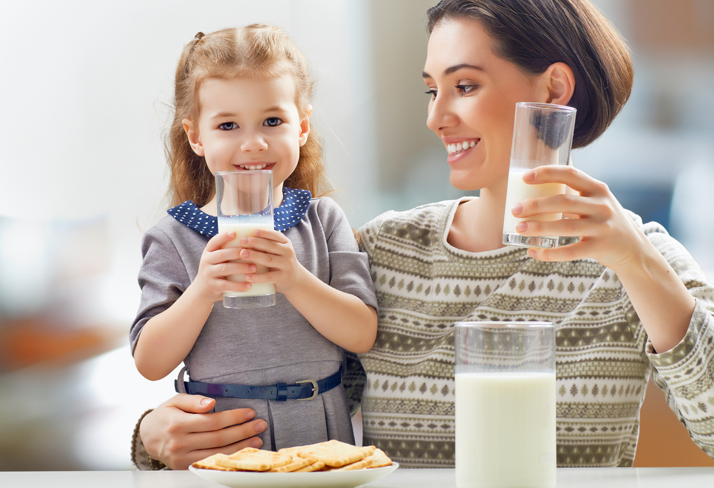 Девочка пьет молоко с мамой
