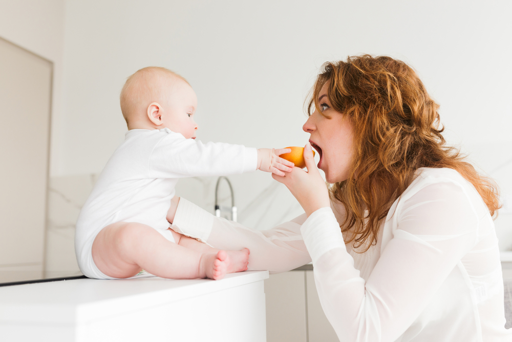 Малыш кормит маму апельсином