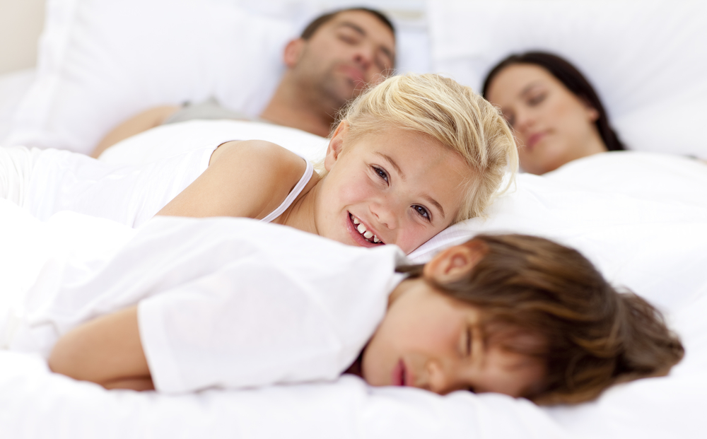 Семья из четырех человек спит в одной кровати