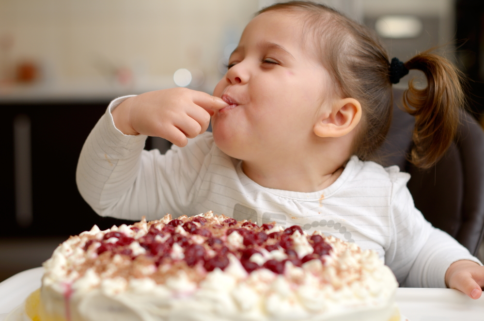 Девочка ест торт с кремом - причины пищевого отравления у детей