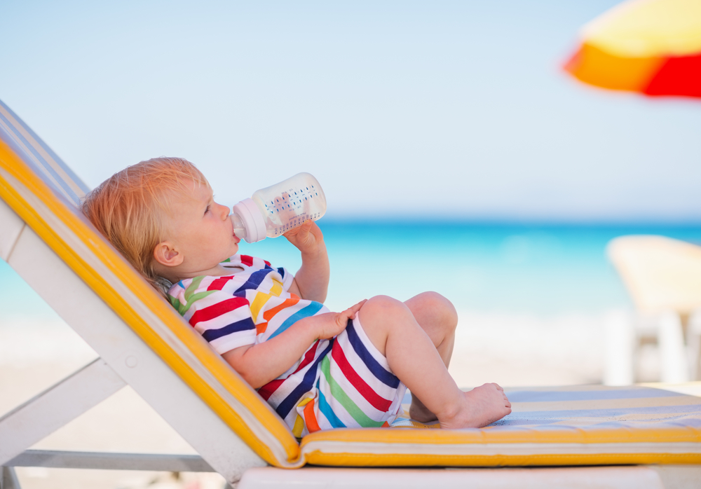 малюк п'є з пляшки на пляжі