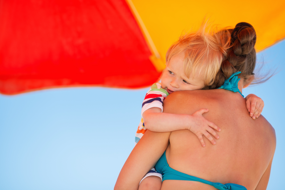 Мама з дитиною під пляжним парасолькою