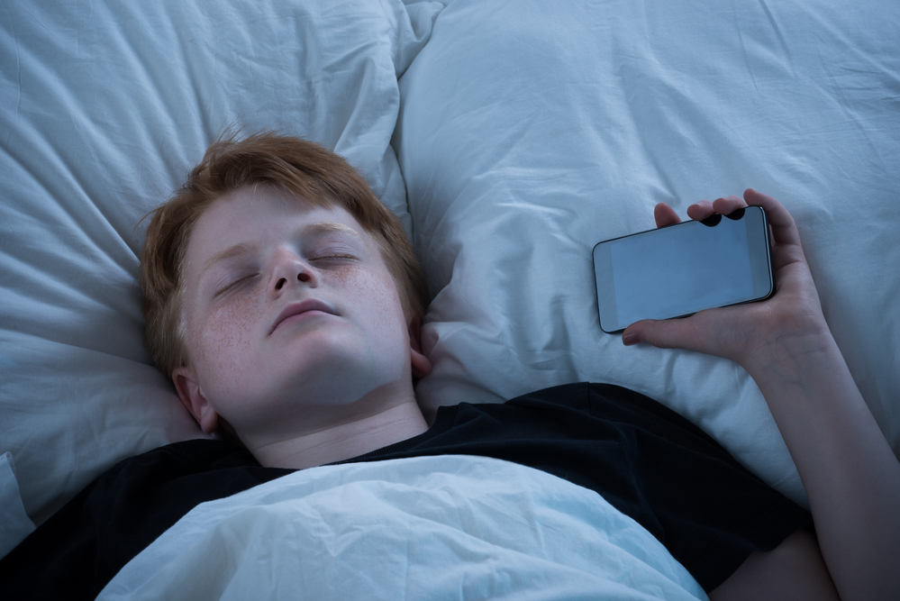 Хлопчик спить з мобільним телефоном