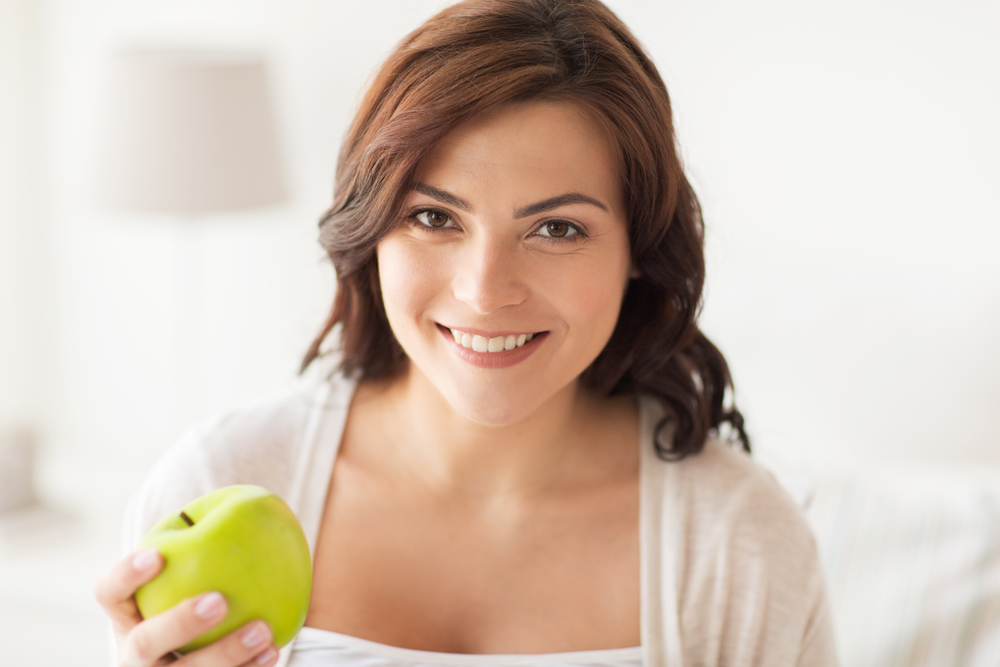 Женщина ест зеленые яблоки