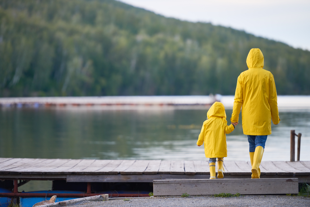 Мама и дочь  у озера в дождевиках желтого цвета