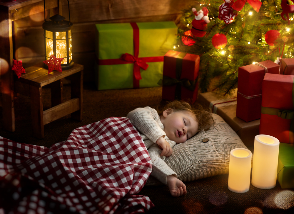 Дитина спить під новорічною ялинкою