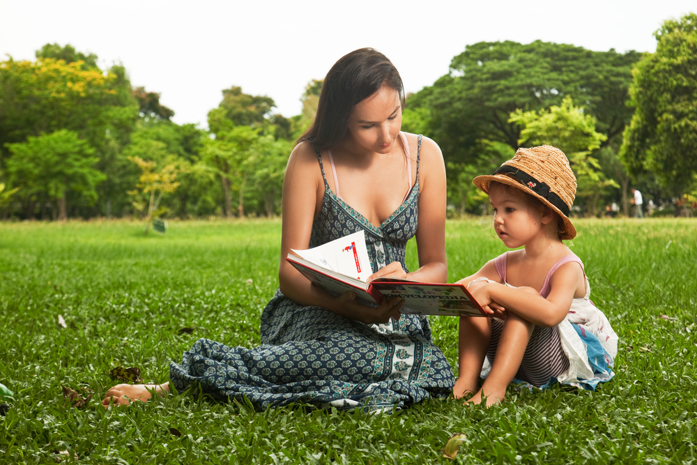 Мама с дочкой на пикнике читают книгу