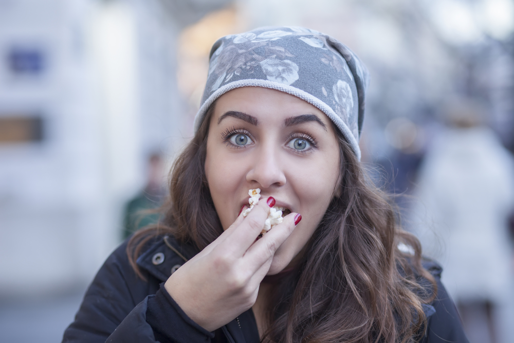 Жінка їсть на вулиці на ходу
