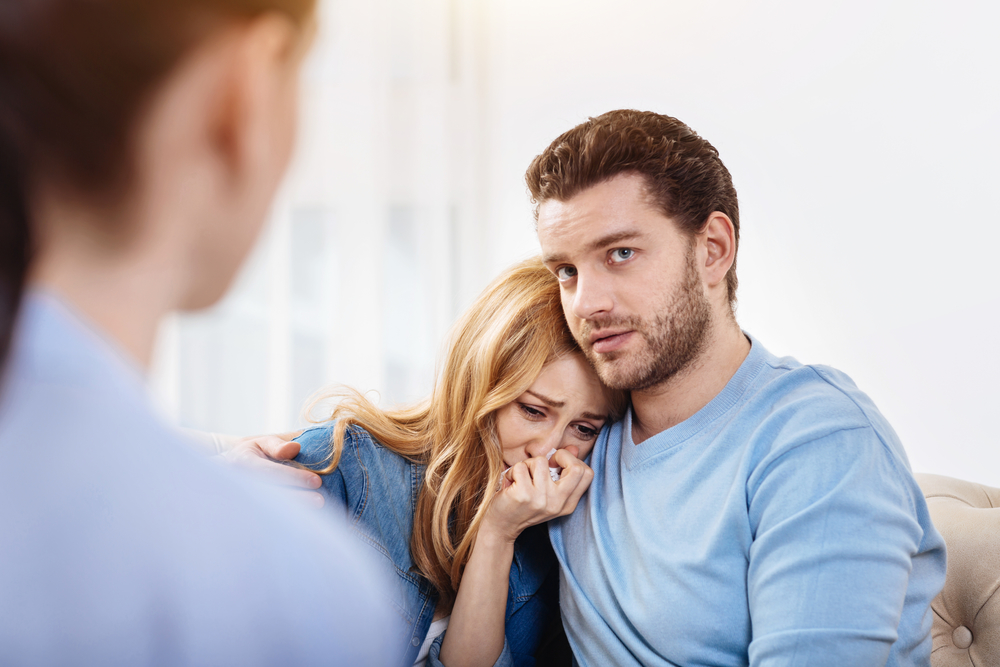 Послеродовая депрессия - муж обнимает жену на консультации у психолога