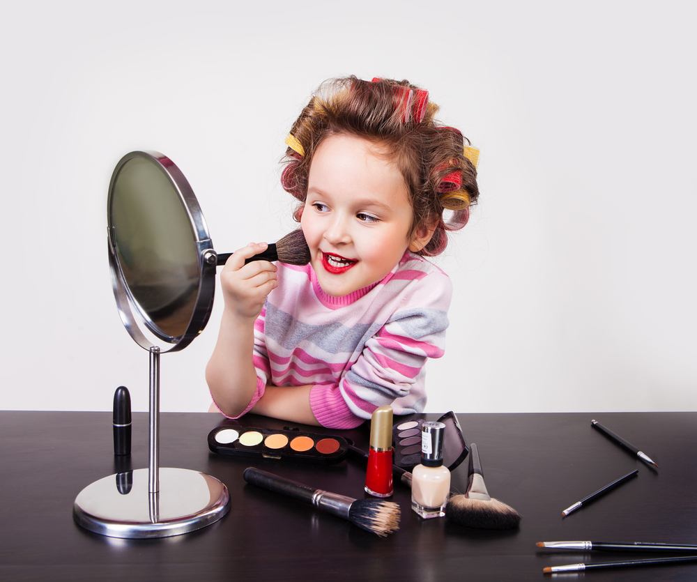 Маленькая девочка наносит макияж