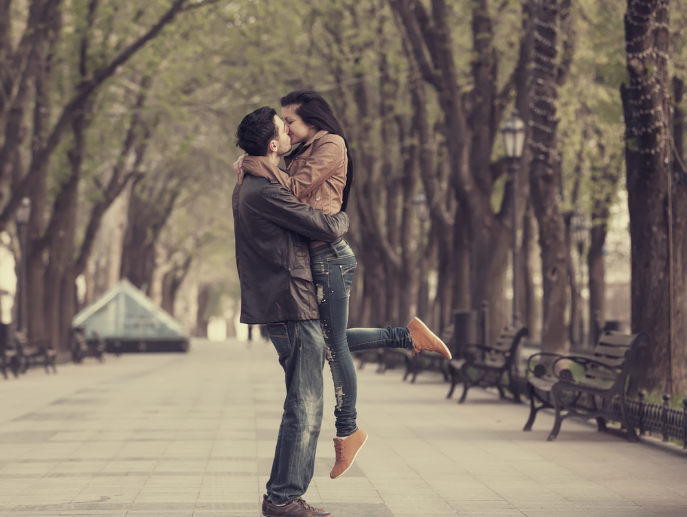 Парень с девушкой целуются в парке