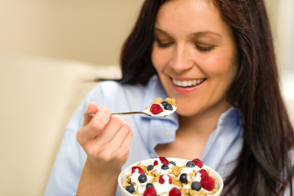 Женщина ест фрукты и злаки с йогуртом