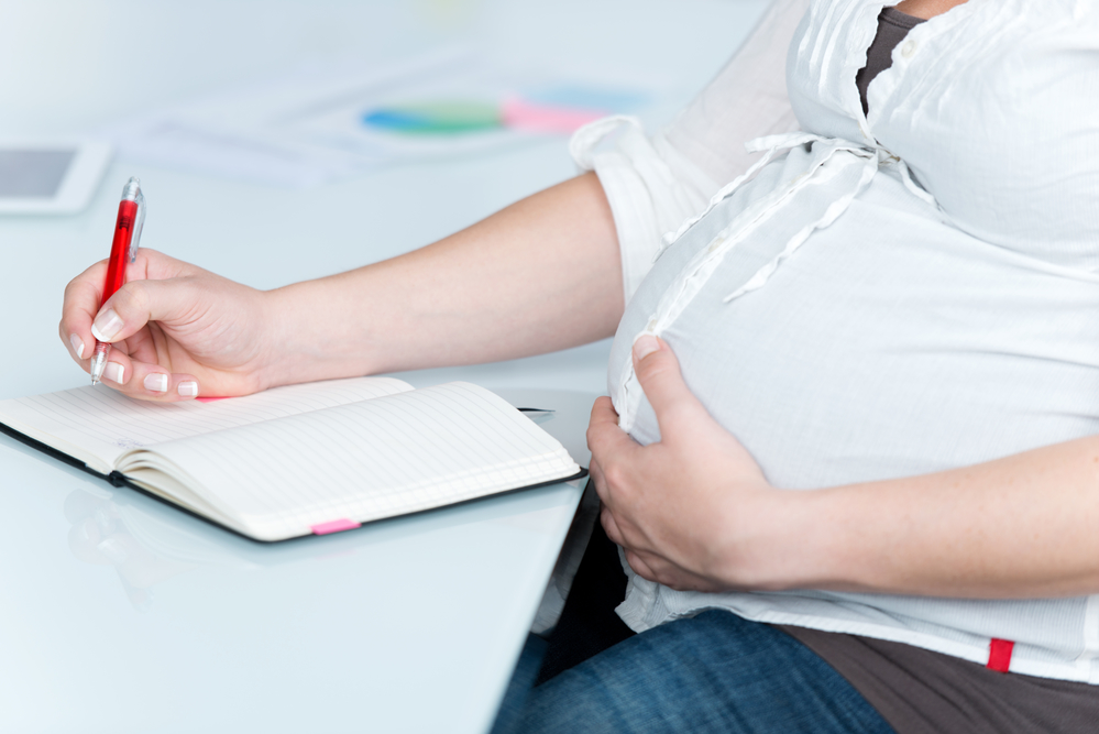Беременная пишет ручкой - оформление декретного пособия