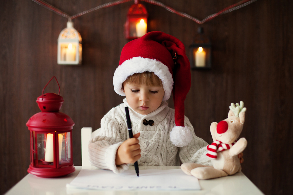 Ребенок в новогоднем костюме пишет письмо