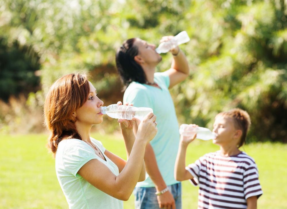 Семья пьет воду из бутылок