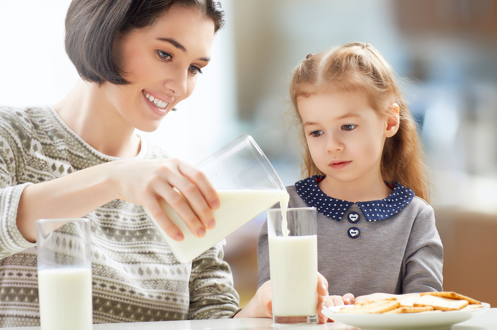 Мама наливає доньці молоко