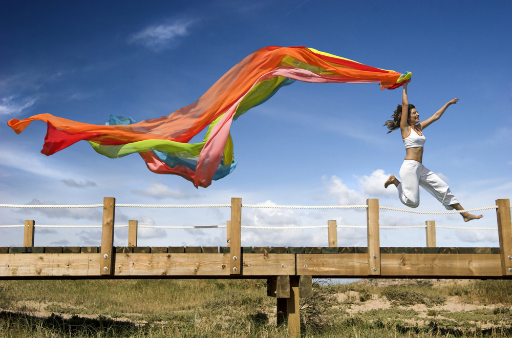 Женщина с ярким шарфом в прыжке