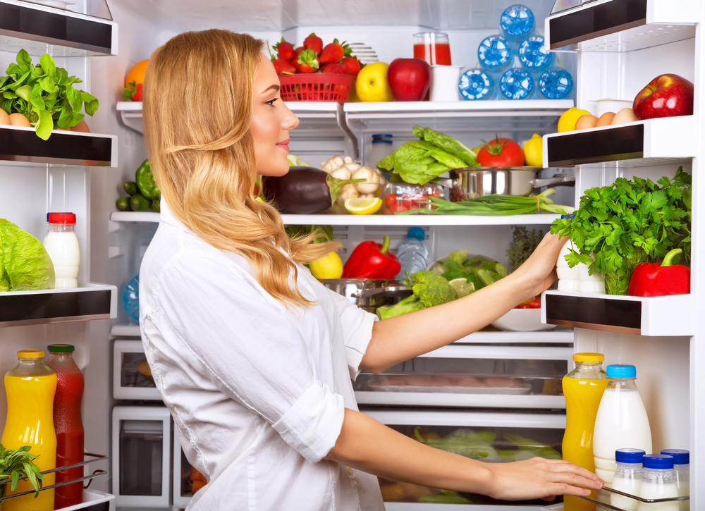 Женщина хранит продукты в холодильнике