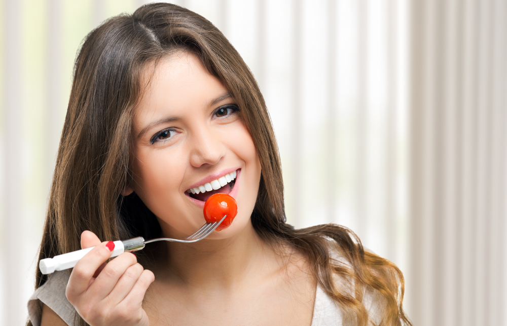 Жінка їсть помідори