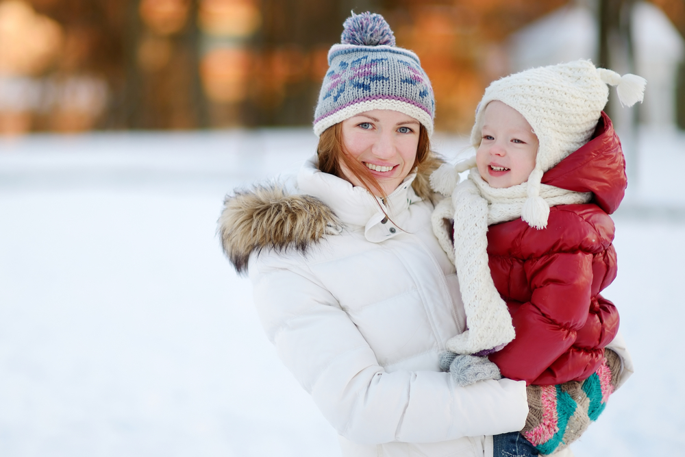 Молода мама з дитиною на руках на зимовій прогулянці
