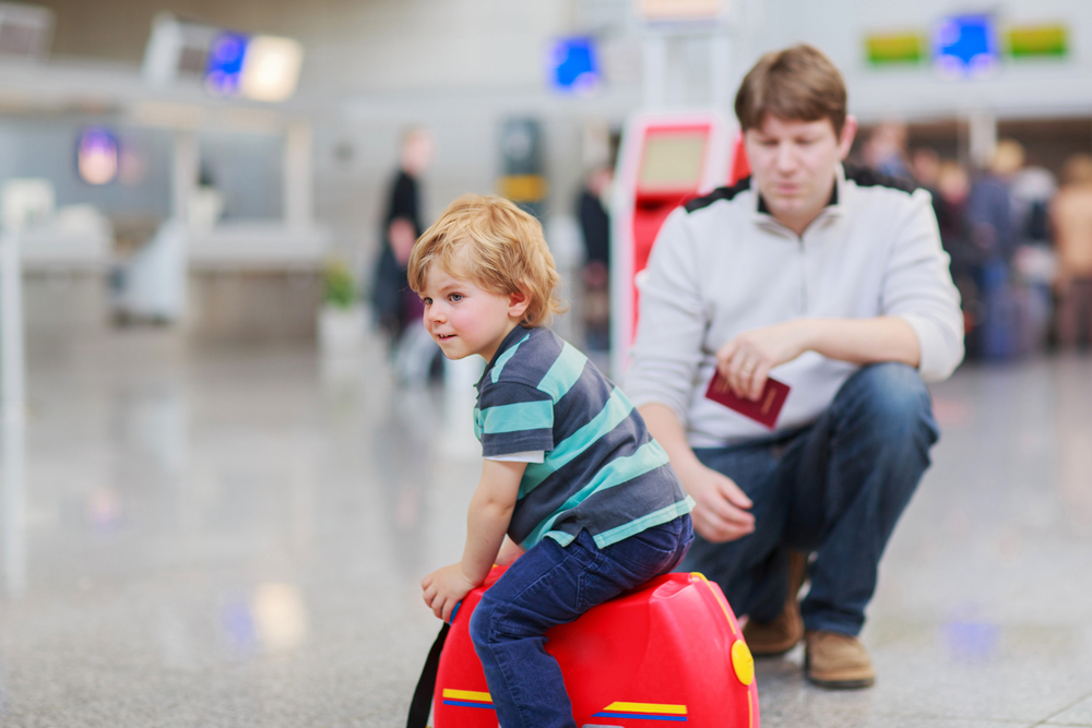 Ребенок сидит на чемодане в аэропорту