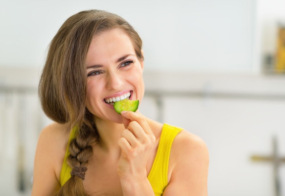 Жінка їсть огірок