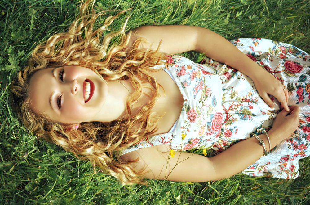Счастливая женщина в платье в цветочек на траве летом