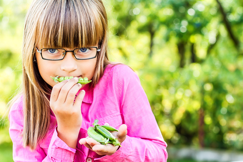 Девочка ест зеленый горошек
