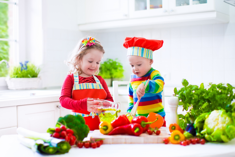 Дети на кухне готовят салат с зеленью