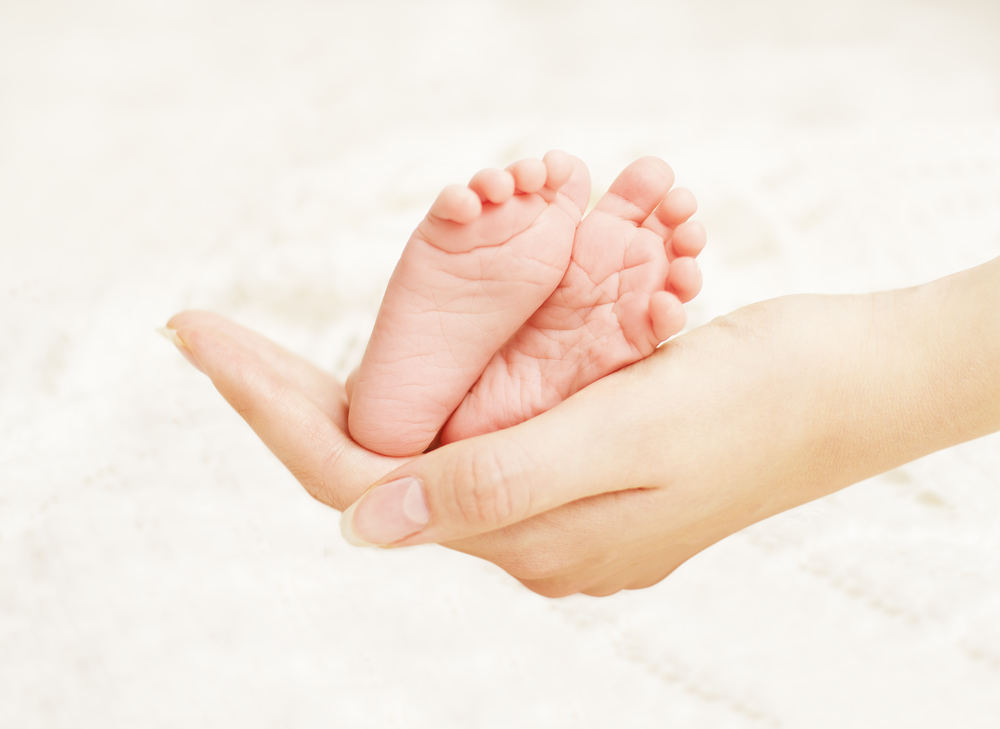 ножки новородженного в руках у мамы