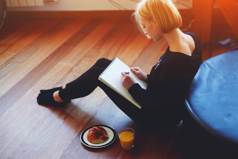 Девушка пишет дневник сидя на полу
