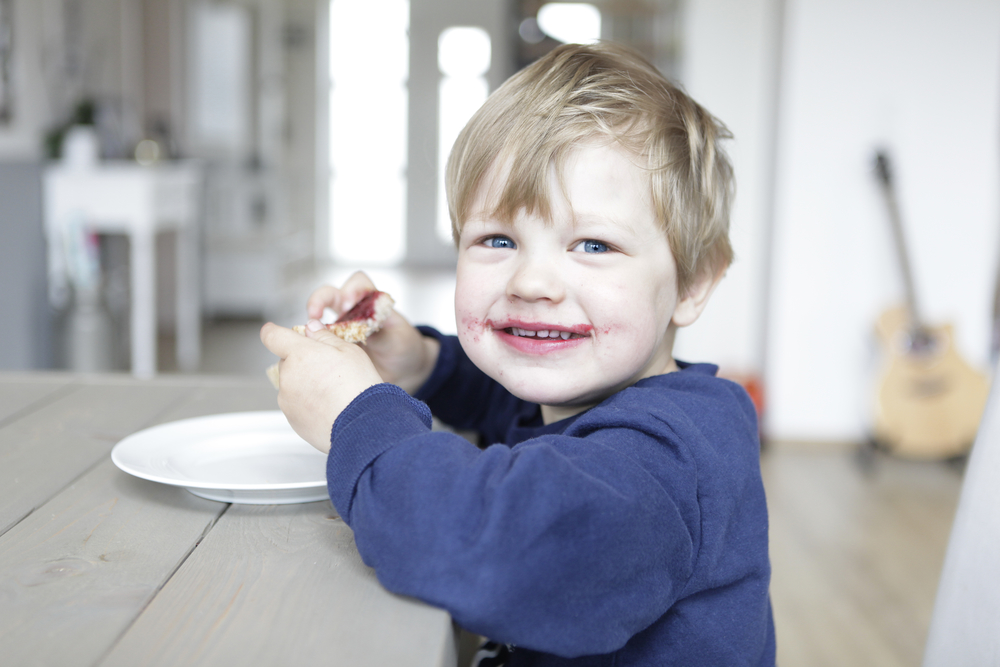 Дитина їсть варення з малини