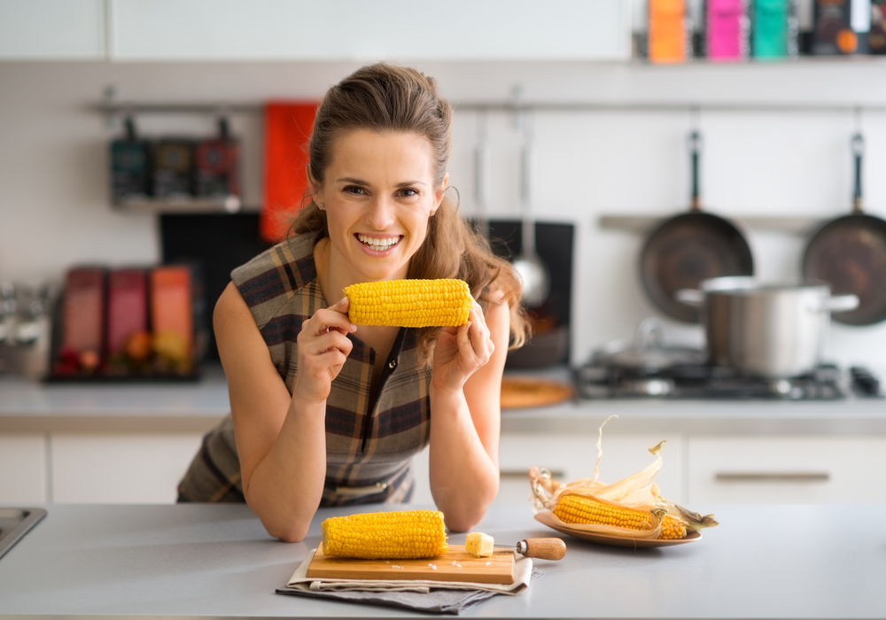 Женщина ест кукурузу