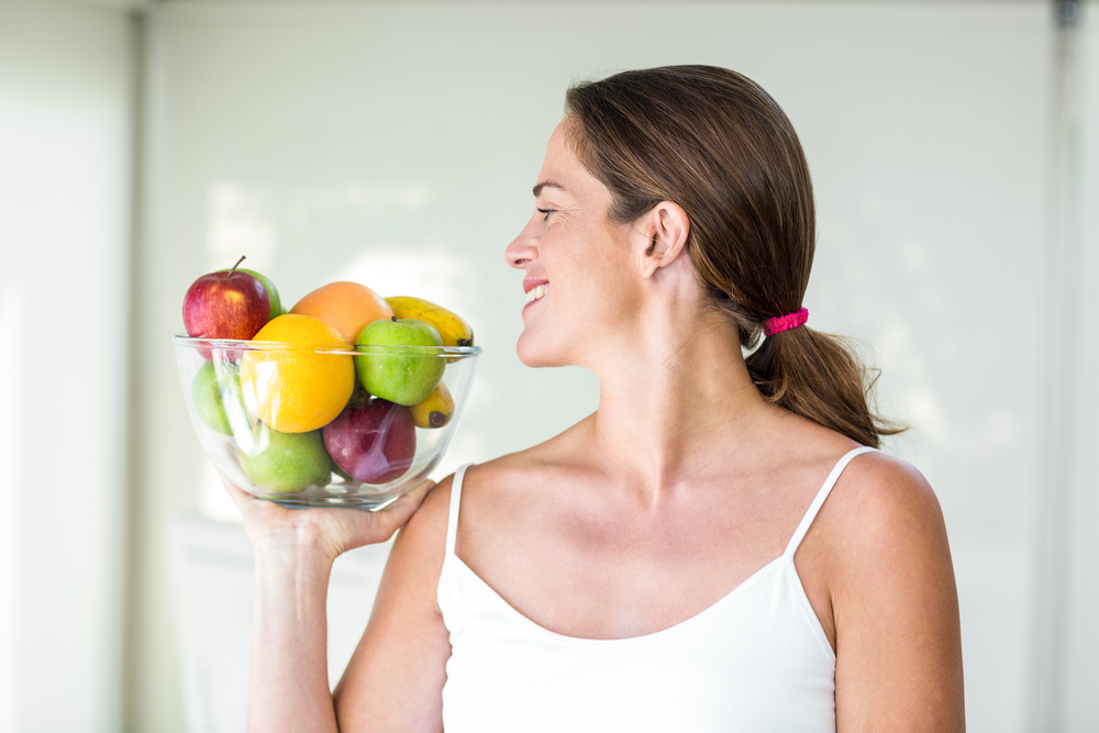 Женщина смотрит на вазу с фруктами