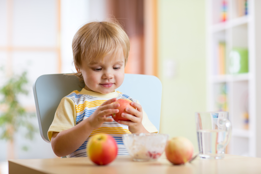 Ребенок ест свежее яблоко