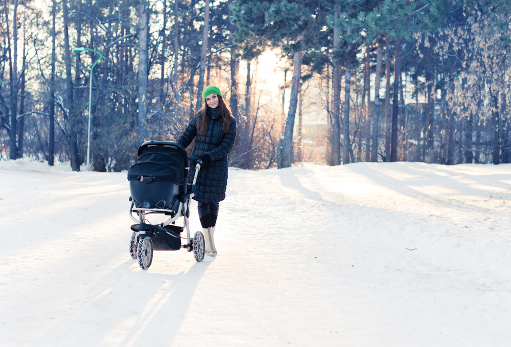 Мама з коляскою дає дитині вітамін Д на сонці взимку