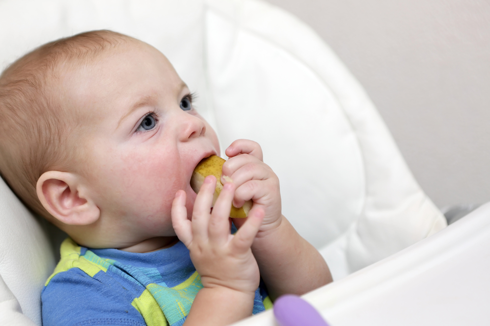 Ребенок ест твердую грушу