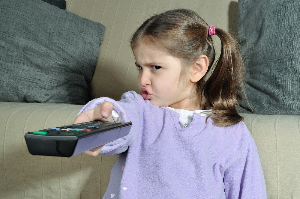Ребенок смотрит телевизор с пультом