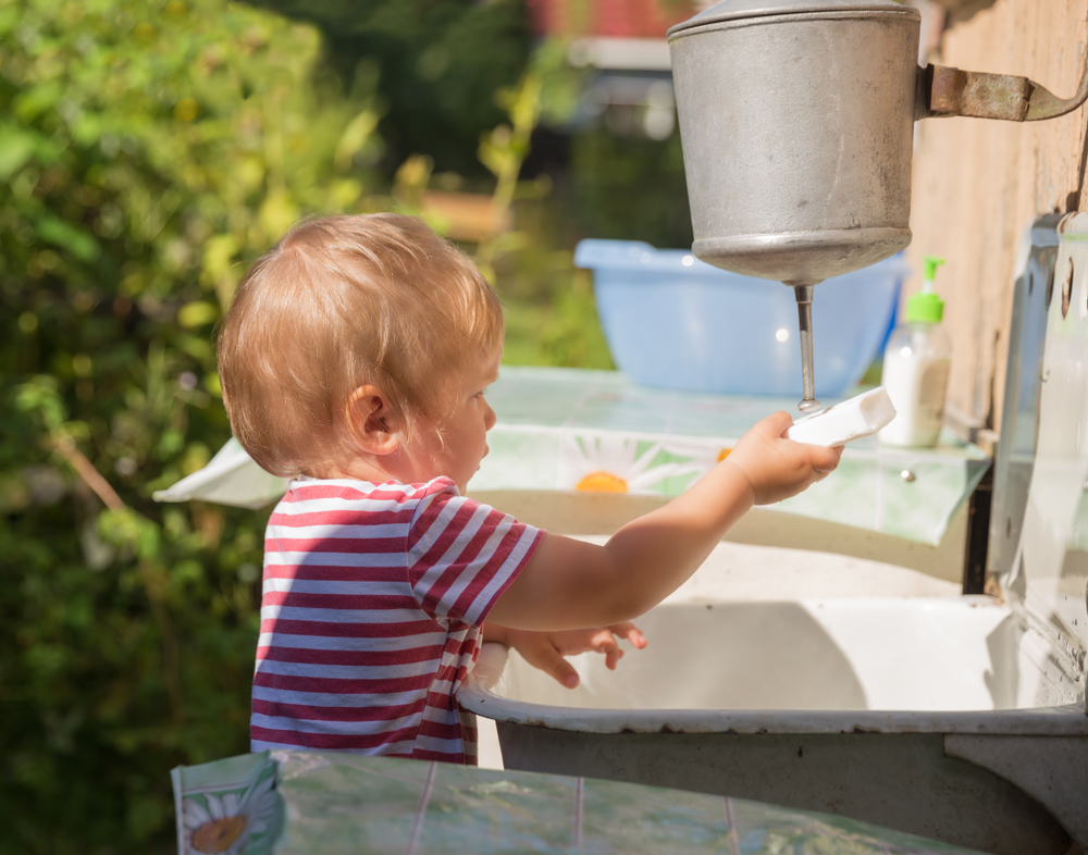 Ребенок моет руки в рукомойнике