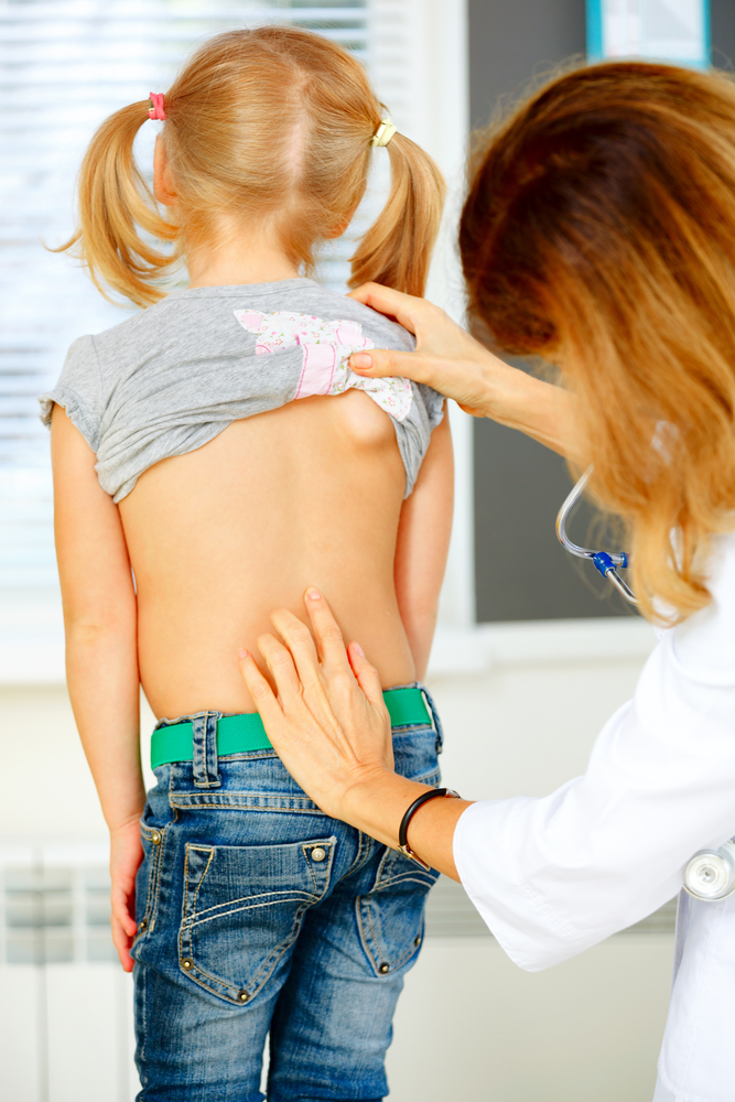 Ортопед осматривает спину ребенка