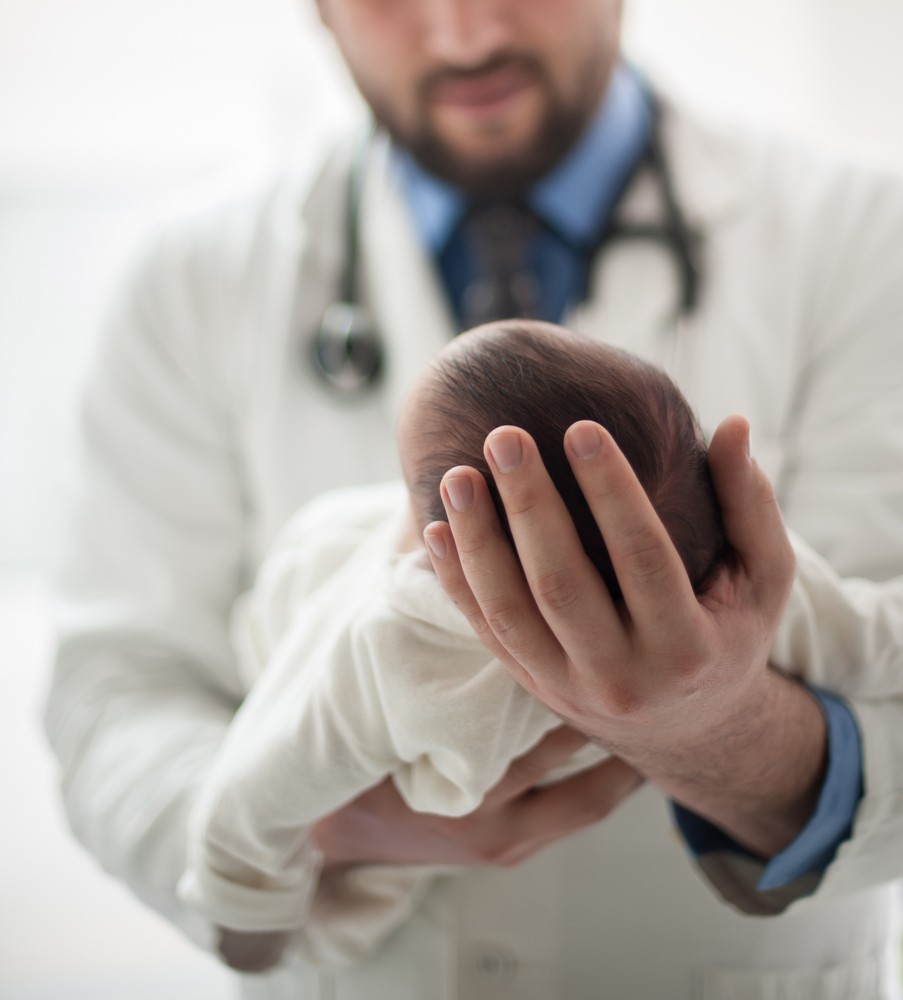 Неонатолог осматривает малыша в роддоме