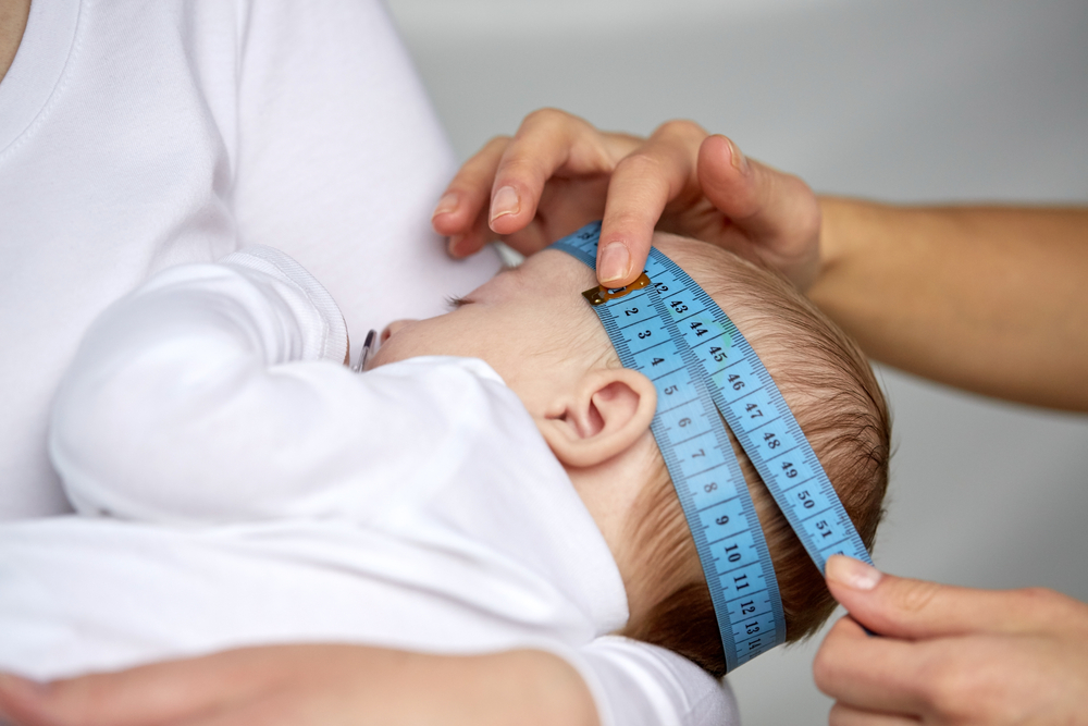 Доктор измеряет окружность головы малыша