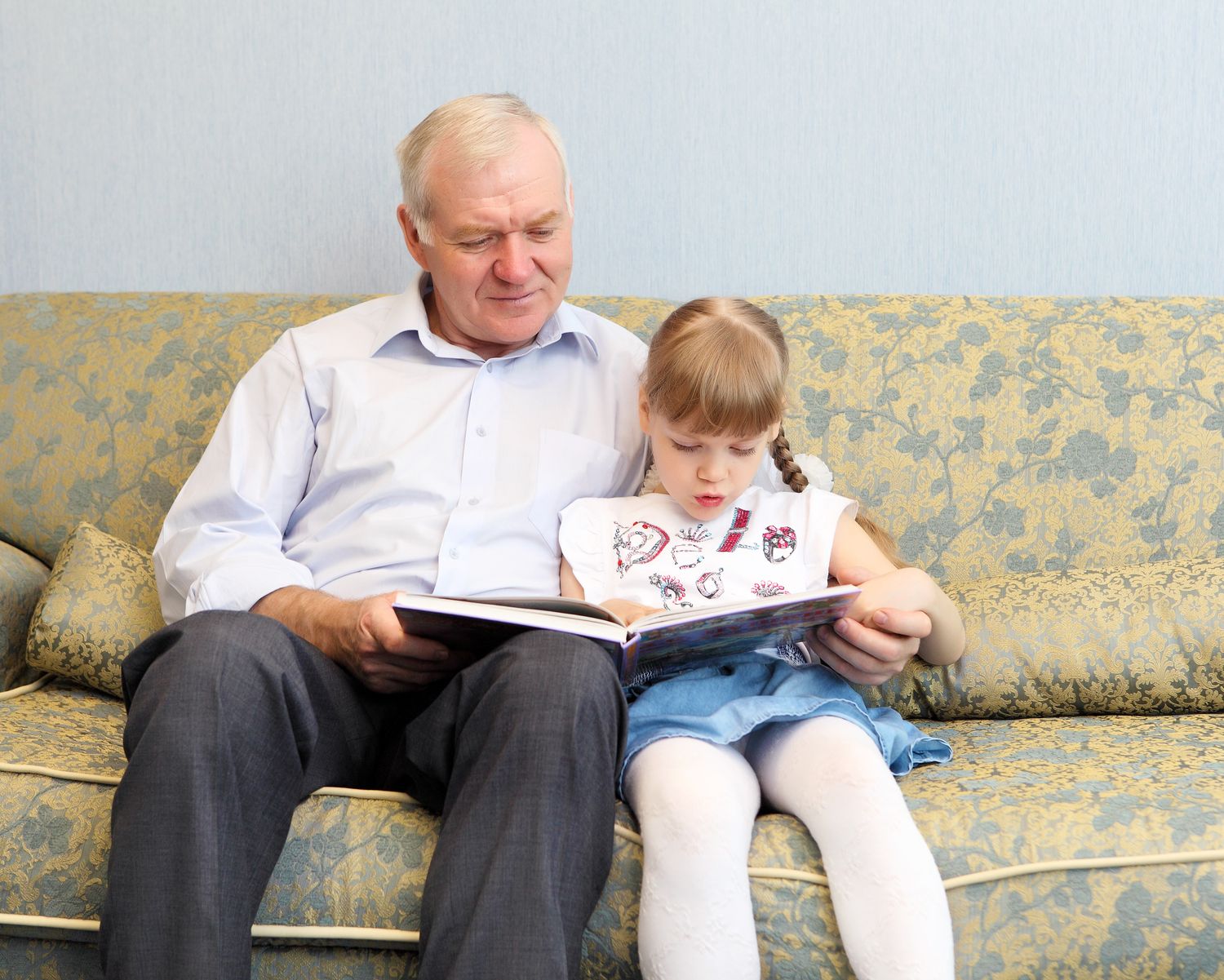 Дедушка с внучкой читают книгу