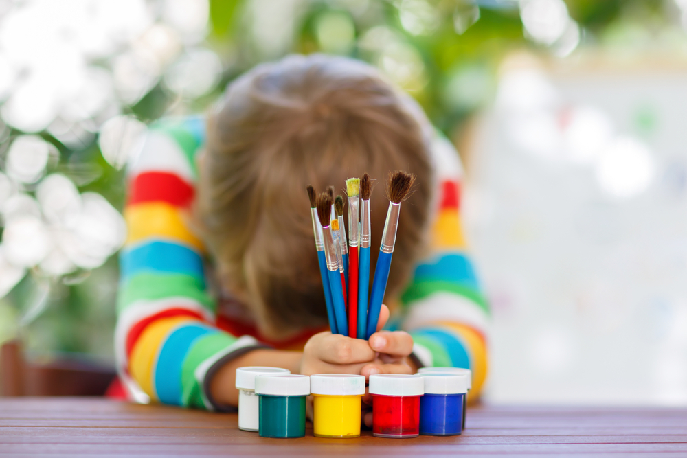 ​Втомлена і засмучена дитина за малюванням у дитячому садку