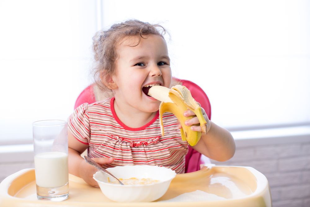 Девочка ест кашу с бананом