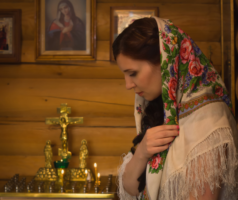 Женщина в платке молится перед иконой Богородицы